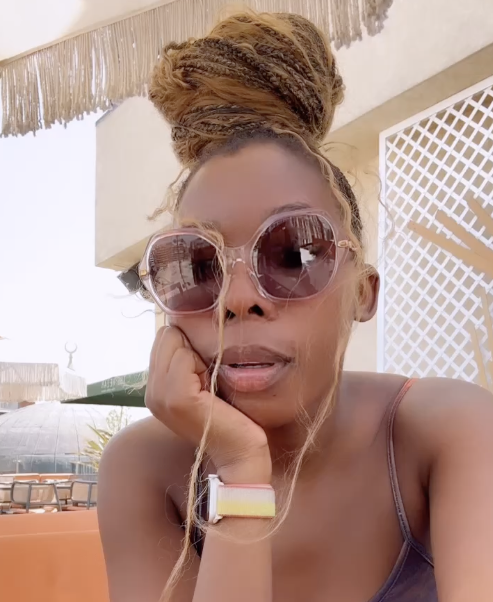 Black girl with braids and sunglasses starting at a camera